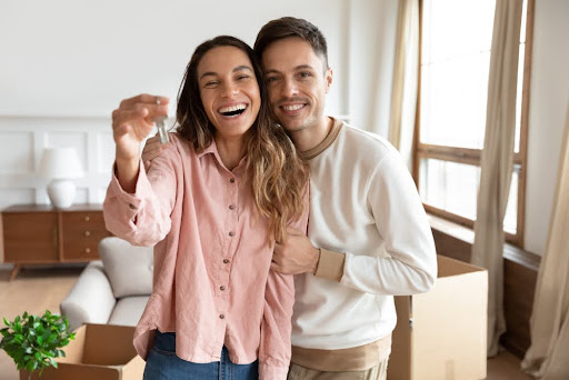 Happy young family couple holding key to new home on moving day concept